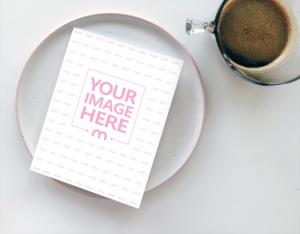 Small Book/Card Next to Cup of Coffee on Table Mockup Generator